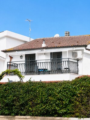 A white building with a tiled roof, a balcony with a metal railing, and an air conditioning unit. - To complete (Anguillara Sabazia)
