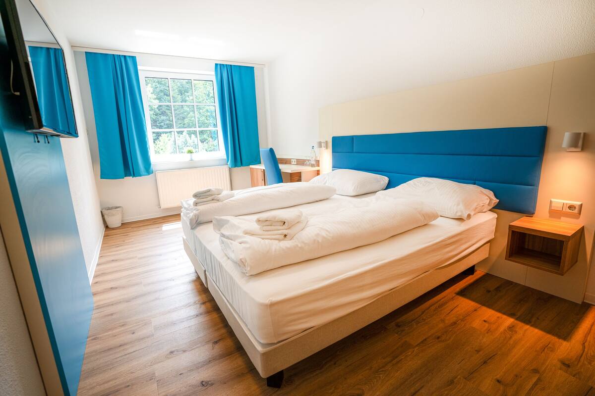 Une chambre d’hôtel moderne avec un grand lit, un bureau et une fenêtre avec des rideaux.