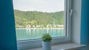 A window with a view of a lake and a hill with buildings. - besttime Hotel Boppard (Boppard)