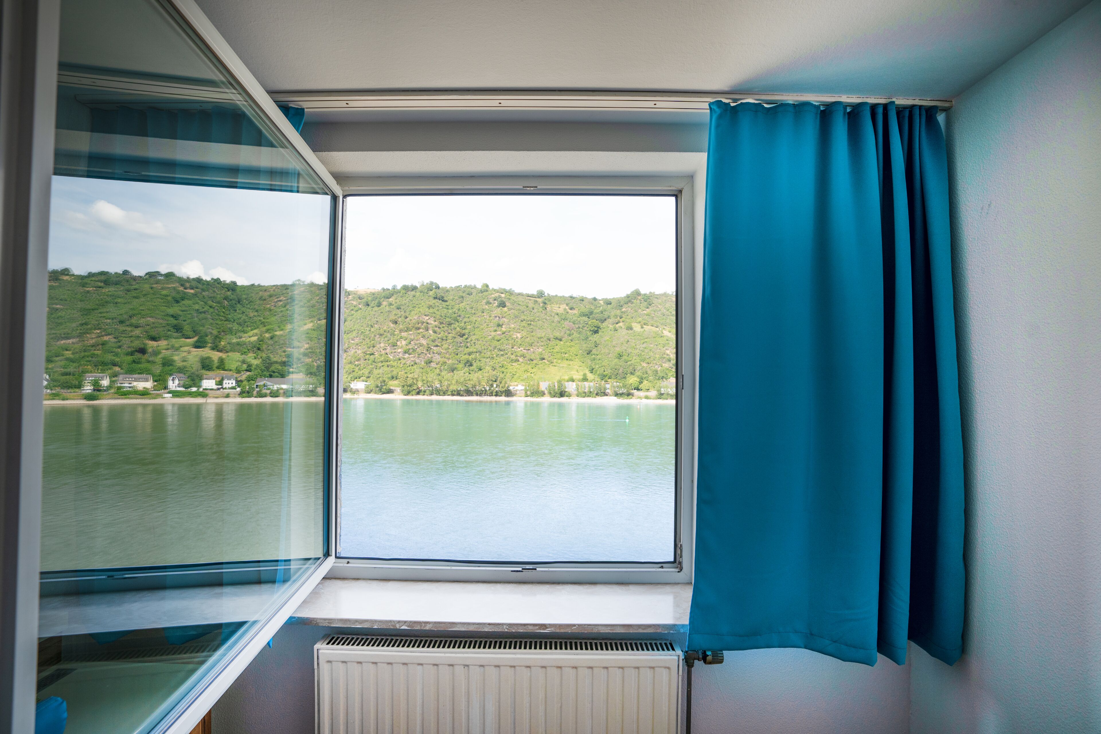 Una habitación con un amplio ventanal que da a un lago y colinas.