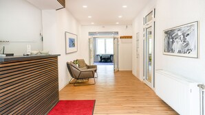 A hotel reception area with a wooden reception desk, a red carpet, a grey armchair, and a framed artwork on the wall. - besttime Hotel Boppard (Boppard)
