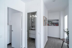 Stylish hallway leads to a bathroom with a sink and shower area.
