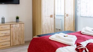 A hotel room with a bed, a wardrobe, a television, and a small plant. - Ferienwohnung Eden Apartments (Friedrichshafen)