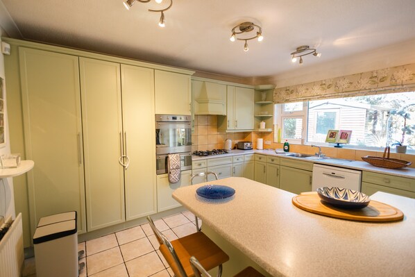 A kitchen with light green cabinets, a central island, and a window with a view of the outdoors.