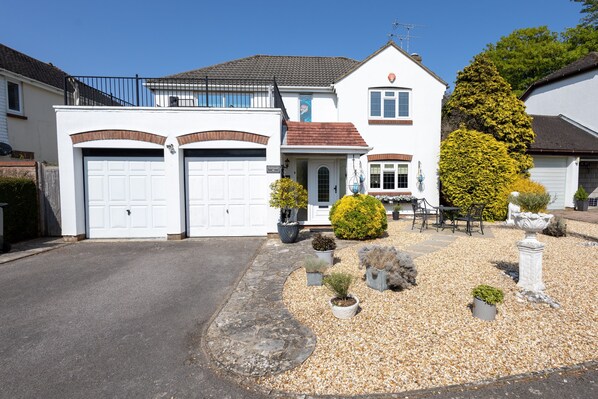 A two-story house with a white exterior, a red-tiled roof, and a front yard with gravel and potted plants. - 'Raggleswood' - a seaside home on Friars Cliff, Mudeford (Christchurch)