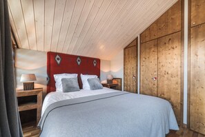 Une chambre à coucher avec un lit, une tête de lit en bois, des tables de chevet et une armoire.