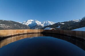 A tranquil pool reflecting a mountainous landscape with snow-capped peaks under a clear sky.