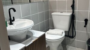 A bathroom with a sink, toilet, and a shower area. - Ap Smart Hub  (Campinas)