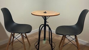 A small room with a round wooden table and two black chairs with wooden legs. - Ap Smart Hub  (Campinas)