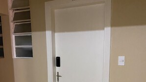 A white door with a small window above it, a doorbell, and a light switch on the wall. - Ap Smart Hub  (Campinas)