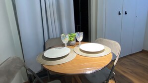 A dining table with two plates, two glasses, and a small plant. - Smart Business Flat (Campinas)