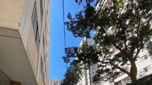 A white car parked on a cobblestone street in a residential area with tall buildings and trees. - Smart Business Flat (Campinas)
