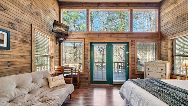 Ein gemütliches Cabin-Interieur mit Sofa, Bett, Esstisch und Wand-Fernseher.