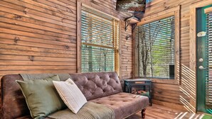 Ein Holzhütten-Interieur mit Ledersofa, Holzwänden und einer grünen Tür.