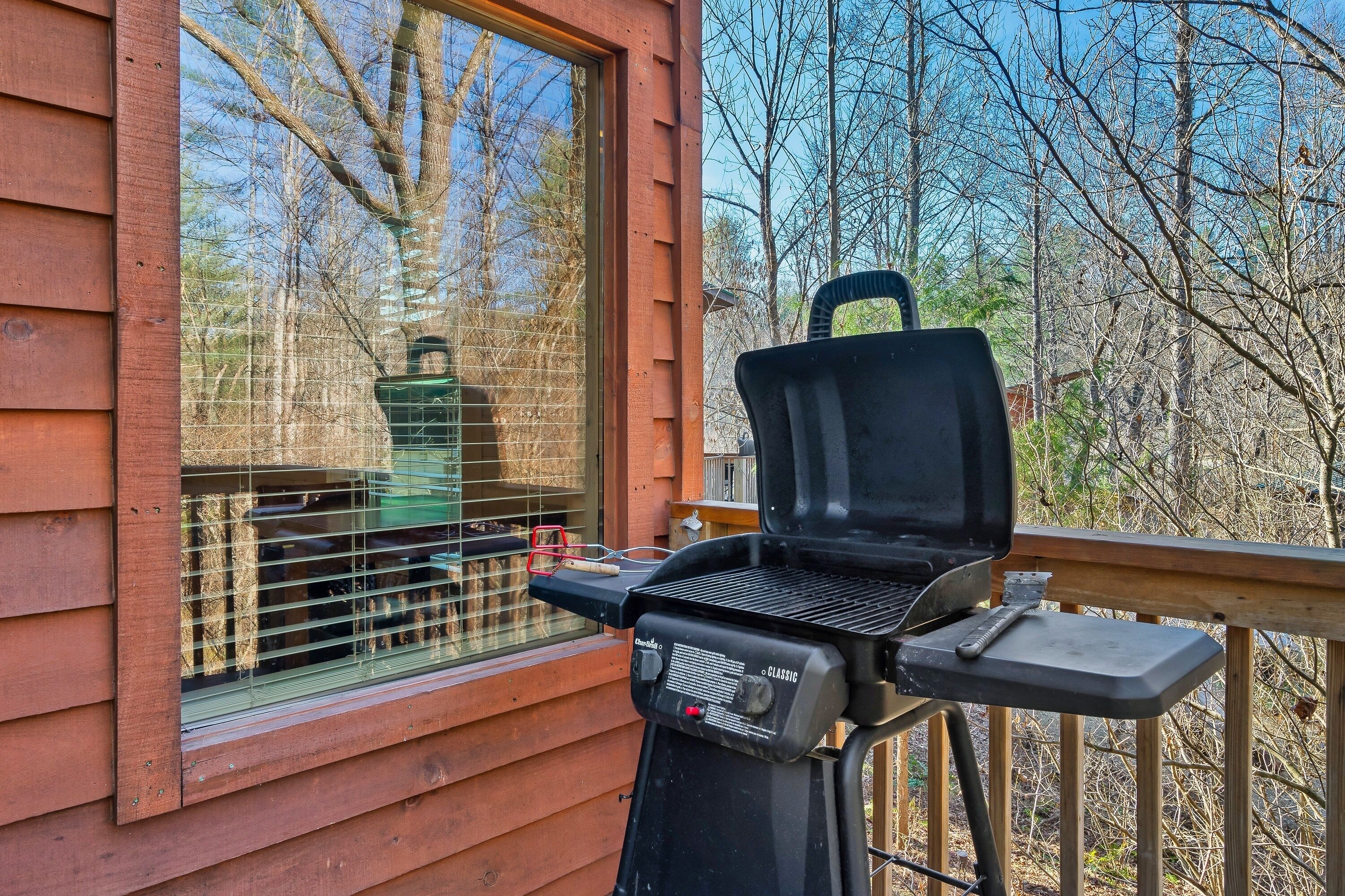 Un barbecue installé sur une terrasse en bois, avec une fenêtre donnant sur une zone boisée.