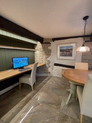 Work and dine in comfort with a desk and dining table, surrounded by a stone wall and a framed picture.