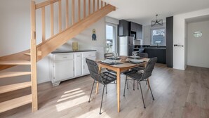 Eine moderne Küche mit weißen Schränken, einer Holztreppe und einem Essbereich mit einem Holztisch und Stühlen.