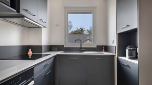 Eine moderne Küche mit dunklen Schränken, einem Fenster über der Spüle und einer kleinen Dekorationsvase.