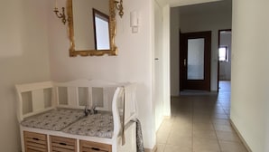 A room with a white crib, a large ornate mirror, and a hallway leading to another room. - Ferienwohnung (Kröppelshagen-Fahrendorf)
