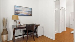 Une pièce comprenant un bureau, une chaise, une lampe et un tableau accroché au mur.