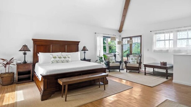 Une chambre à coucher avec un lit en bois, deux tables de chevet, un banc, une chaise et une petite table.