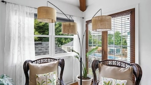 Une pièce avec deux fauteuils en osier, une plante en pot et une vue sur un balcon.