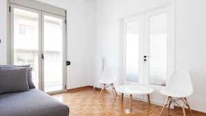 Una sala de estar moderna con un sofá gris, dos sillas blancas y una mesita.