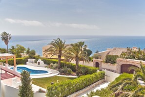 A resort with a swimming pool, palm trees, and a view of the ocean. - Casablanca (Xàbia)