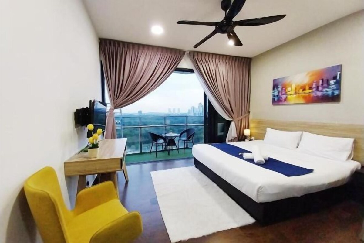 A hotel room with a bed, a desk with a chair, a balcony with a table and chairs, and a city view.