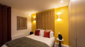 A hotel room with a bed, bedside tables, a mirror, and a wall-mounted light fixture. - Au pied de la Tour, 1BR/1BA, 4 people (París)