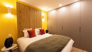 A modern bedroom with a bed, bedside tables, a wardrobe, and a wall-mounted light fixture. - Au pied de la Tour, 1BR/1BA, 4 people (París)