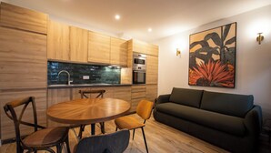 A modern kitchen with wooden cabinets, a dining table with chairs, and a sofa in a living area. - Au pied de la Tour, 1BR/1BA, 4 people (París)