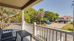 Varanda coberta com mesa e cadeiras, com vista para uma área residencial com árvores e uma casa.