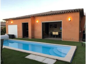 A house with a swimming pool, a garage, and a dining area.