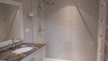 Un baño con lavamanos de mármol, ducha y baldosas de suelo estampadas.