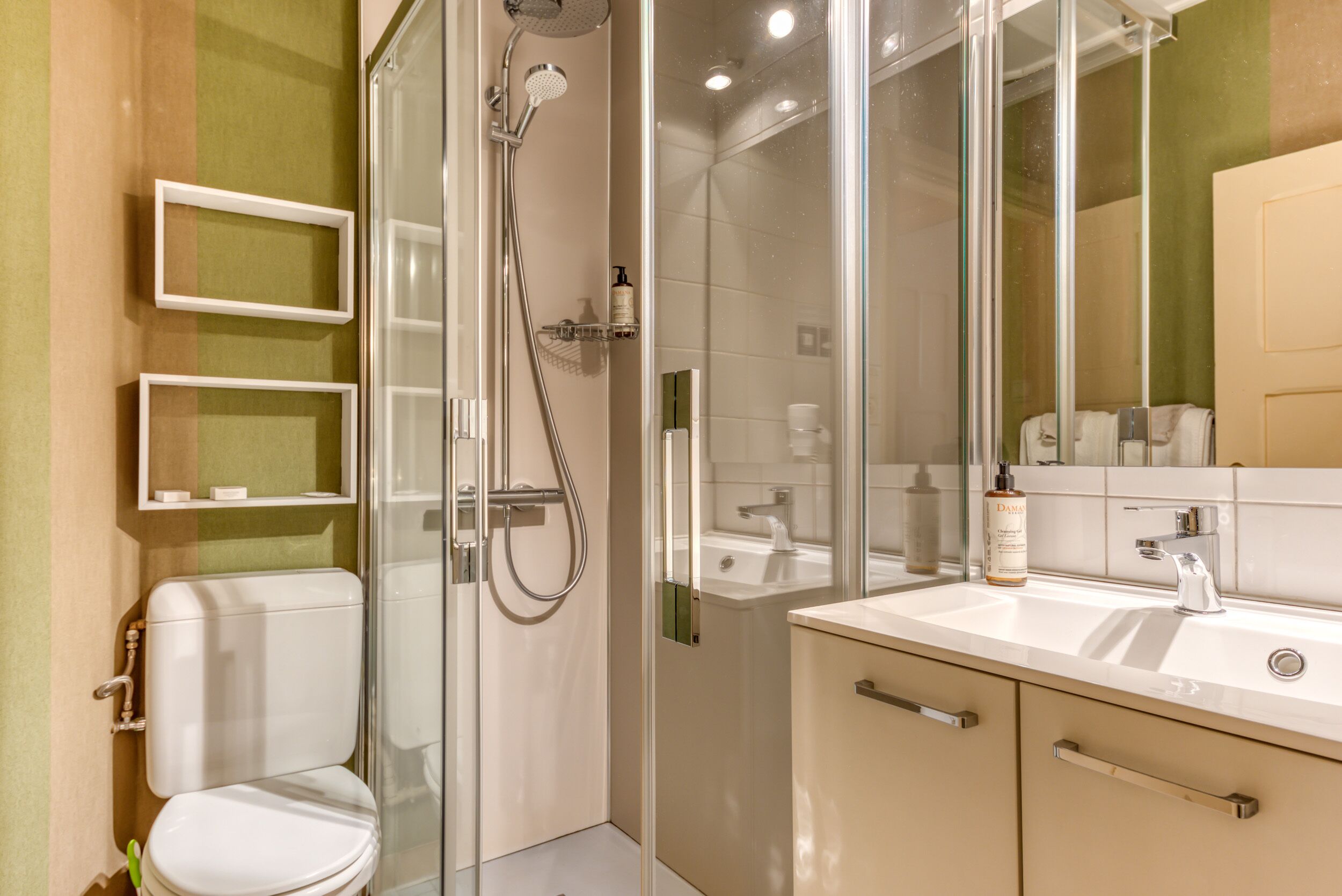 Un baño moderno con ducha envuelta en vidrio, inodoro, lavamanos y espejo.