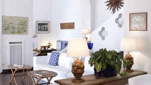 A modern living room with a white sofa, two side tables with lamps, a potted plant, and wall art. - La Villa, luxury villa with private sea access (Campania)