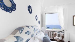 A bedroom with a bed, a window with a view of the sea, and decorative wall mirrors. - La Villa, luxury villa with private sea access (Campania)