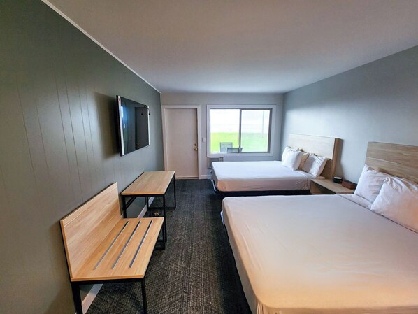 A hotel room with two beds, a TV, a desk, and a window with a view of the outdoors. - The Birchy, Adventure Lodging by Base Hospitality Group (Marquette)