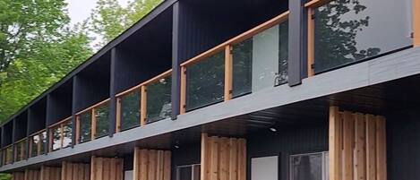 A modern building with a flat roof, large windows, and a wooden deck.