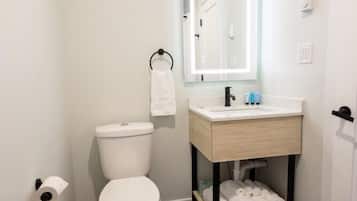 Une salle de bain comprenant des toilettes, un lavabo avec un miroir et un porte-serviettes.