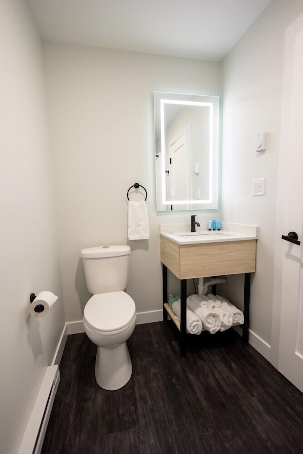 Un baño con inodoro, lavabo con espejo y toallero.