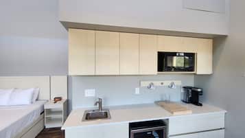 A compact kitchenette with a microwave, sink, and coffee maker.