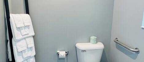 Un baño pequeño con un inodoro, un perchero y un cubo de basura.