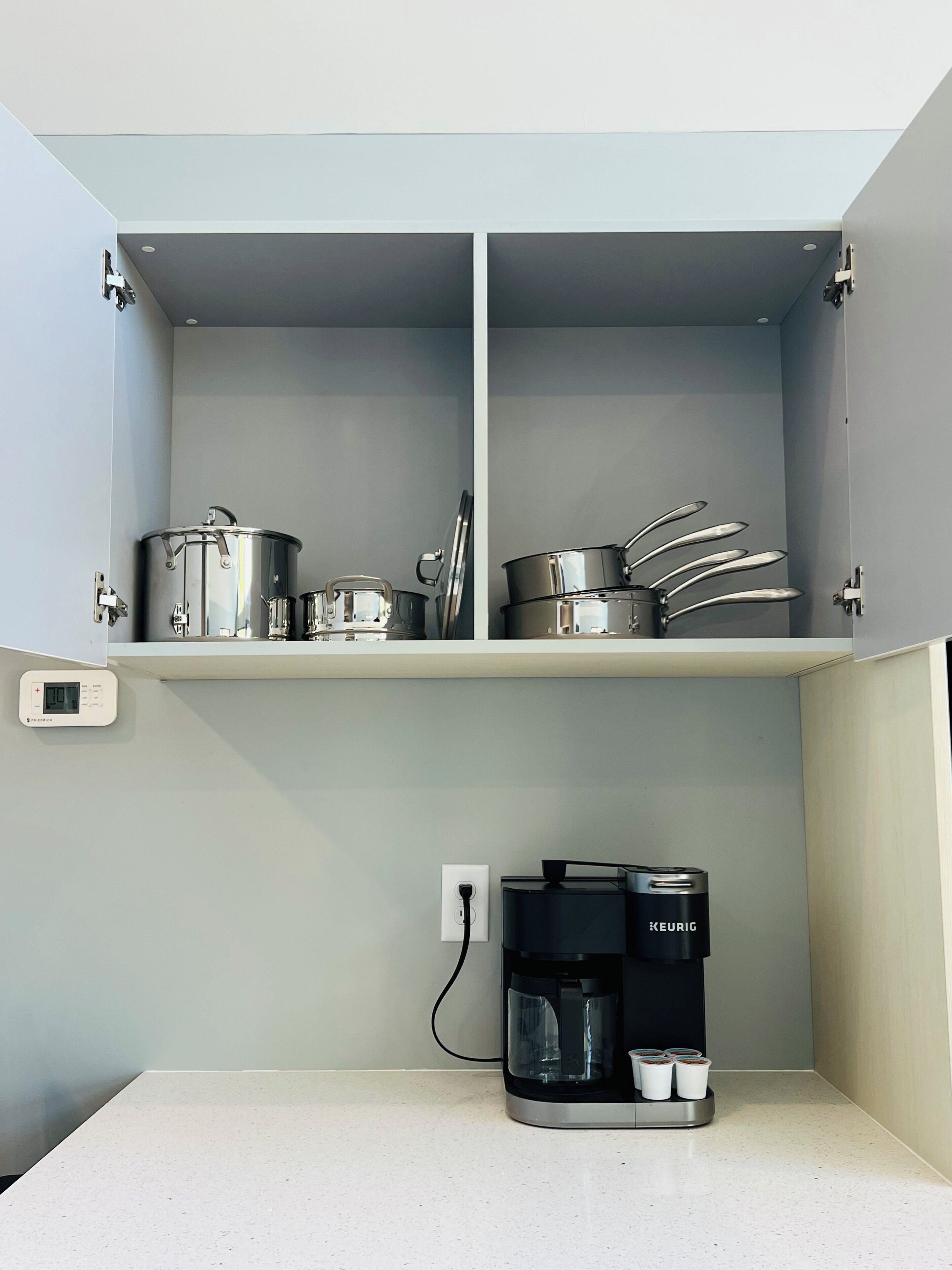 Una cucina con una macchina da caffè, una bilancia e pentole in acciaio inossidabile sul piano di lavoro.