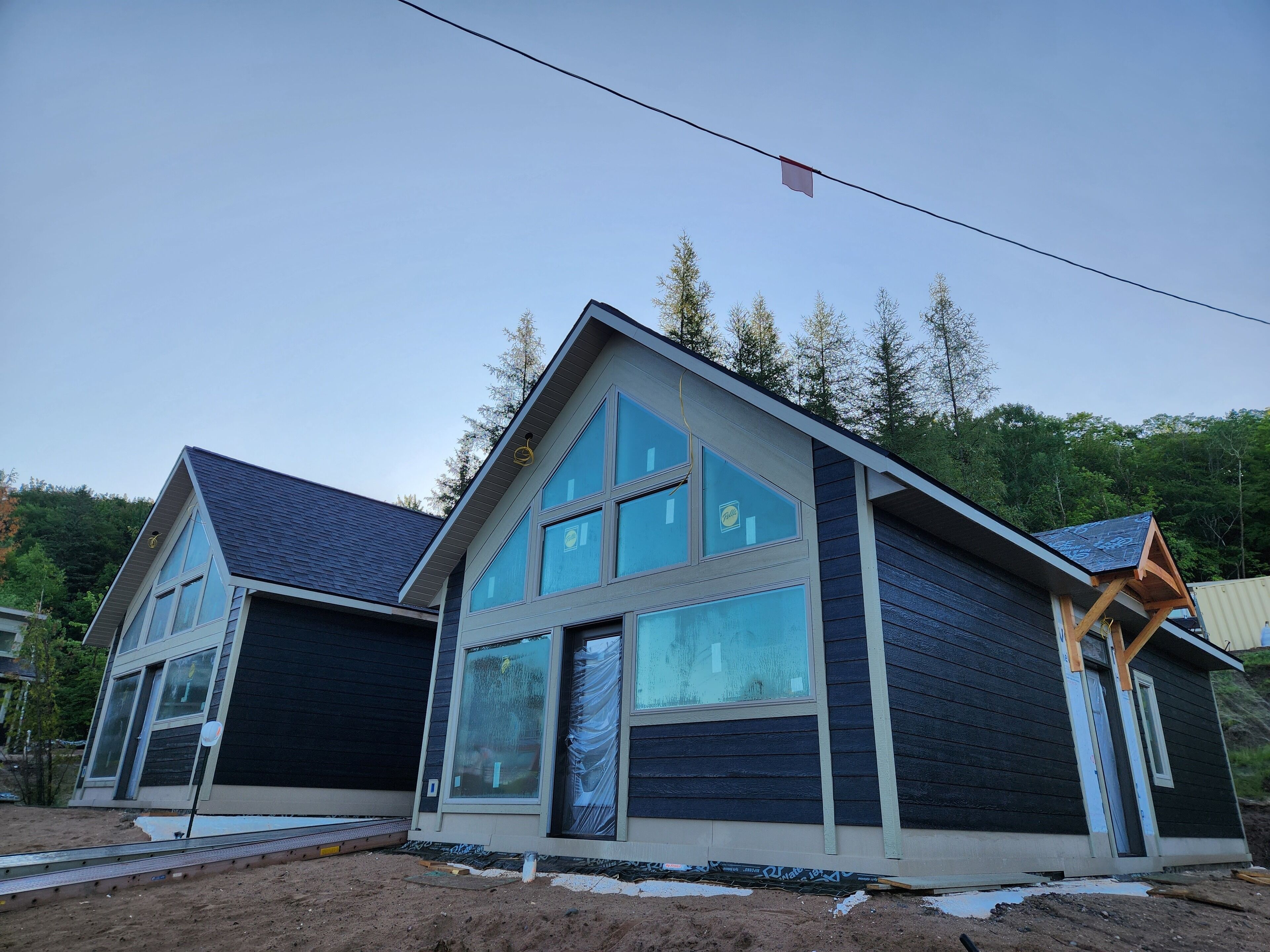 A modern two-story house with large windows, a garage, and a wooden porch.