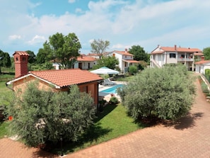 Bairro residencial com casas, piscina e chaminé de tijolos.