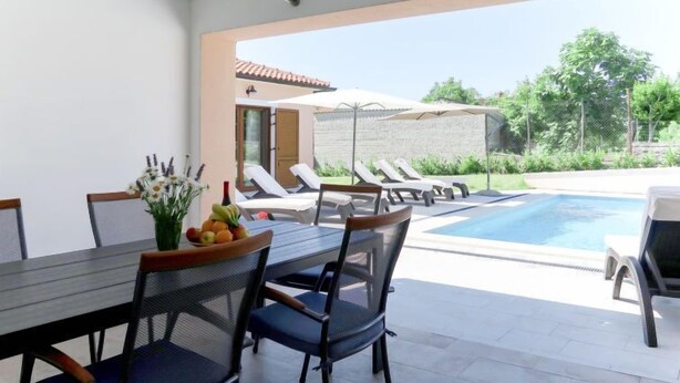 Un espace extérieur aménagé pour les repas, avec une table et des chaises, une piscine et des chaises longues.