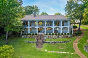 A two-story house with a stone facade, multiple balconies, and a front staircase leading to the entrance. - Lake Hamilton Dock + Hot Tub + Arcade | Sleeps 16 (Hot Springs)