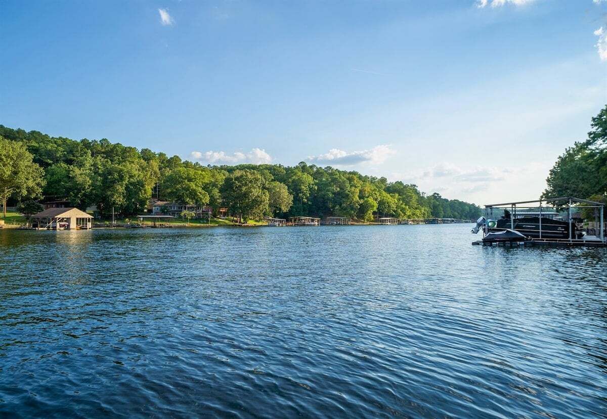 Un lac paisible où sont amarrés des bateaux, un kiosque et, au loin, une colline boisée.